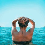 woman on holding her head while standing on body of water