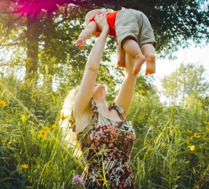 woman carrying baby near grass