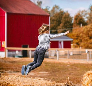 girl wearing white and black striped long sleeved shirt jumping outdoor
